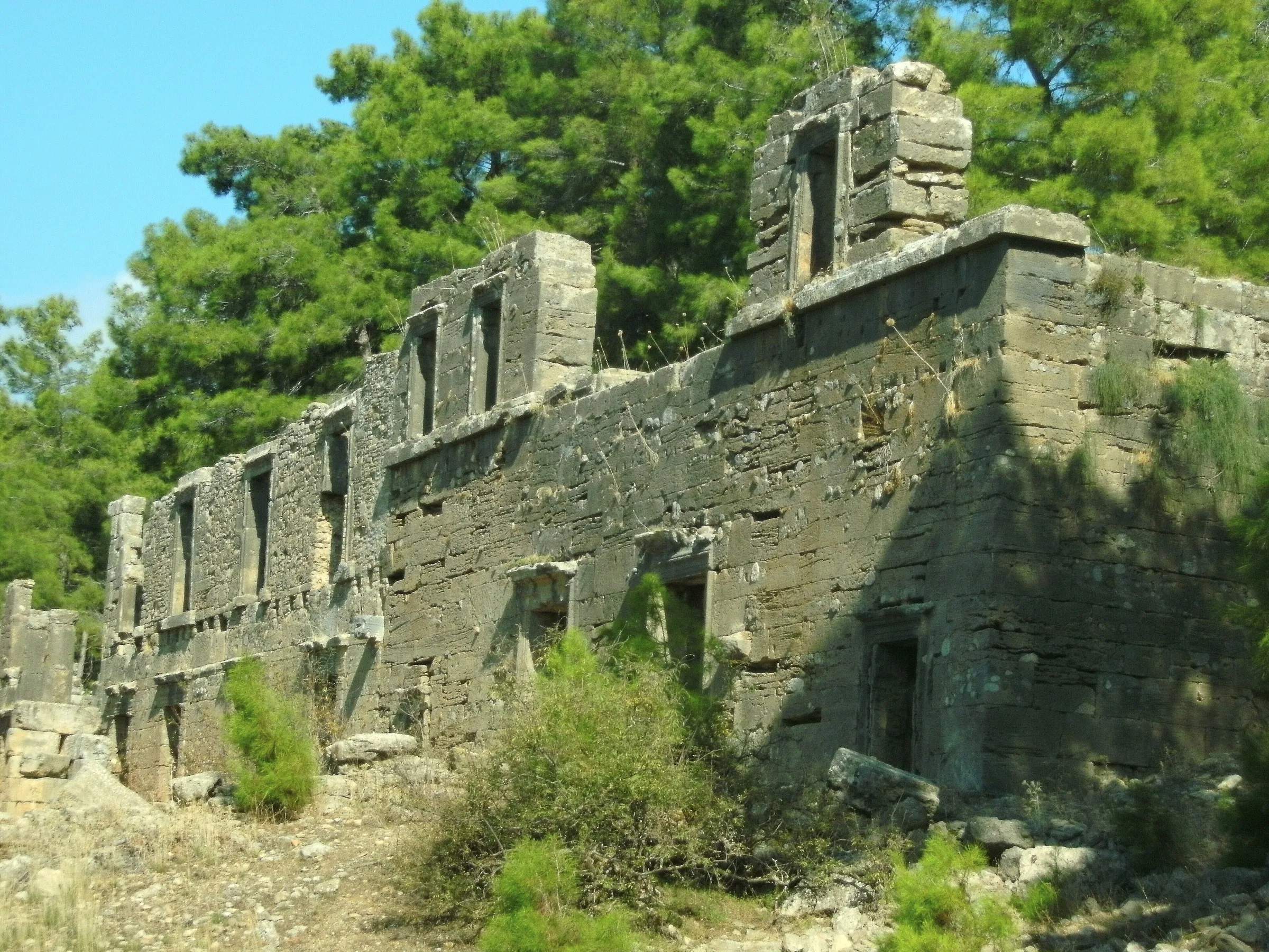 The two-storey shop façade of the agora at Seleukeia (Lyrbe), door and window openings intact, pine forest behind